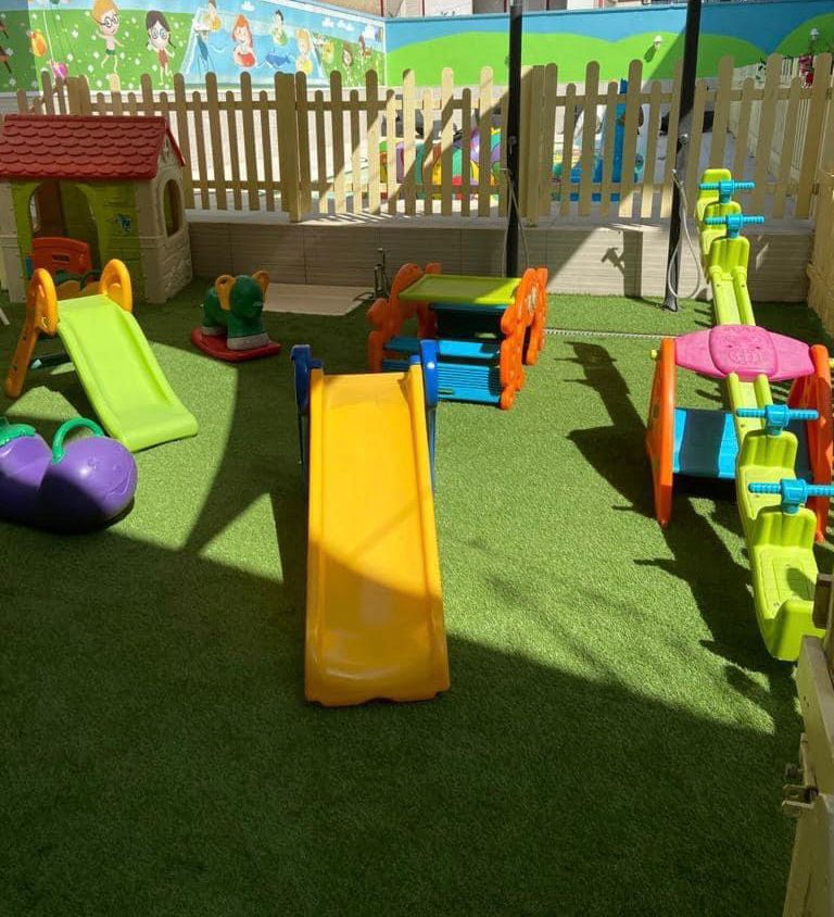 Area giochi all'aperto con scivoli colorati su prato sintetico